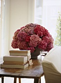 A detail of a traditional sitting room, wooden side table, pink hydrangea flowers