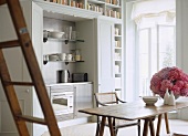 A modern, compact kitchen built in and concealed behind cupboard doors, wood dining table, chairs