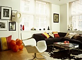 Modernes Wohnzimmer mit weißem Sessel und schwarzem Sofa mit Couchtisch auf Tierfell