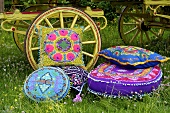 Colourful ethnic cushions in front of a carriage on a field