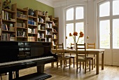 A piano in a living-room-cum-dining-room in front of a window and a balcony door
