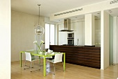 A dining area with a green table in an open-plan kitchen with a wooden counter