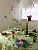 Farbige Gedecke auf grüner Tischdecke im Esszimmer mit weisser Holzverkleidung
