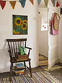 A rustic wooden chair on a striped rug and an open, white-painted door