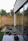 A shiny terrace floor with decorative stones in front of a house and a brick wall in the background