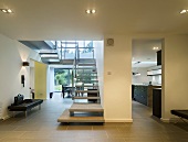 An anteroom with an open stairway and a view into the kitchen and the living room