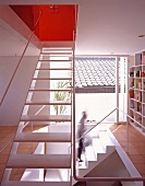 Offenes Treppenhaus mit eingebauten Bücherregalen und raumhohes Fenster