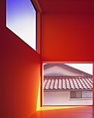 An empty, red-painted room in newly built house with floor-to-ceiling windows