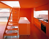A stairway dividing an open-plan, red-painted kitchen from a living room