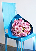 A bunch of roses in blue paper on a blue chair
