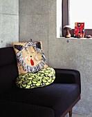 Detail of a sofa with a cushion against a concrete wall