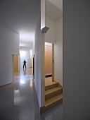 A simple anteroom with a highly polished tiled floor and a view of a staircase behind a wall