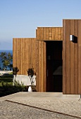 A wood panelled house face with an open front door