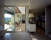 A modern living room with a partially open terrace door and a view of a table and chairs