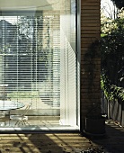 A corner of a house with blinds at the floor-to-ceiling windows