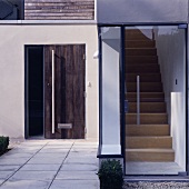 A glazed entrance to a modern house with a view of the stairs and an additional wooden front door