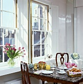 Marmortisch, für das Frühstück gedeckt, vor den Fenstern mit weissen Fensterläden