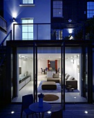 A terrace of a newly built house in the evening with an illuminated living room