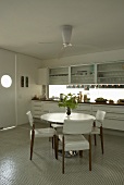 A dining table with upholstered chairs in front of a white kitchen counter in modern kitchen