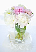 Peonies in a vase on a lace cloth