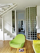 A green armchair next to a flight of stairs in a living room