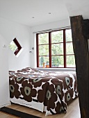 A double bed with a brown patterned quilt in a bedroom