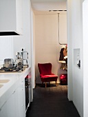 A view from a narrow kitchen onto a red chair