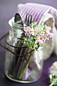 Cutlery and napkins in a jar with a handle decorated with baby primroses