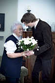 Enkel überreicht Grossmutter Blumenstrauss zum Geburtstag