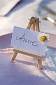 A place card with the name 'Anne' on a mini easel with a daisy