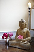 Buddhastatue und Blumenvase im Yoga-Übungsraum