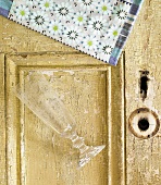 Leeres Sektglas & Serviette auf alter Tür liegend