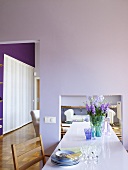 A long dining table in a high dining room with pink walls