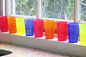 Colourful plastic cups on a window sill
