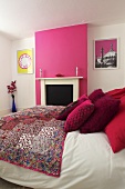 A double bed in a bedroom with pink and white walls