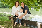 A young family sitting on the bank of a lake