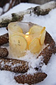 Brennende Kerze in einer Eisschale mit Zitronenscheiben