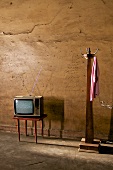 alter Fernseher auf Tischchen, neben Garderobenständer aus Holz