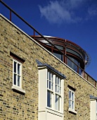 Ziegelfassade mit Erker aus weisser Metallverkleidung eines Wohnhauses mit Glas-Rotunde auf dem Dach