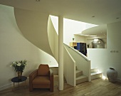 Brown retro leather chair in front of a winding staircase in a modern living room