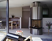 An open plan living room-cum-dining room with a stainless steel fireplace next to a flight of stairs