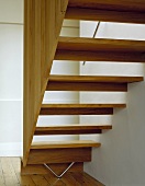 Offene Treppenstufen und Geländerpanel aus Holz auf Dielenboden