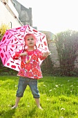 Little girl with umbrella in garden