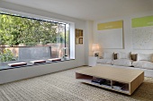 A wooden cubic coffee table on a rug in a modern living room with a large picture window