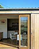 House with open patio door and view on a modern dining area with white chairs