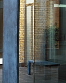 View through a narrow opening between two steel supports and glass facade of a bench