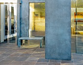 Tiled lobby and steel room divider in front of a bench by a bank of windows