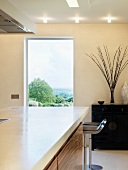 Kitchen unit with white countertop in front of a window with a view of the countryside in a designer kitchen