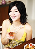 Young woman holding a glass of pink champagne in her hand
