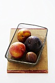 Different types of plums in a wire basket